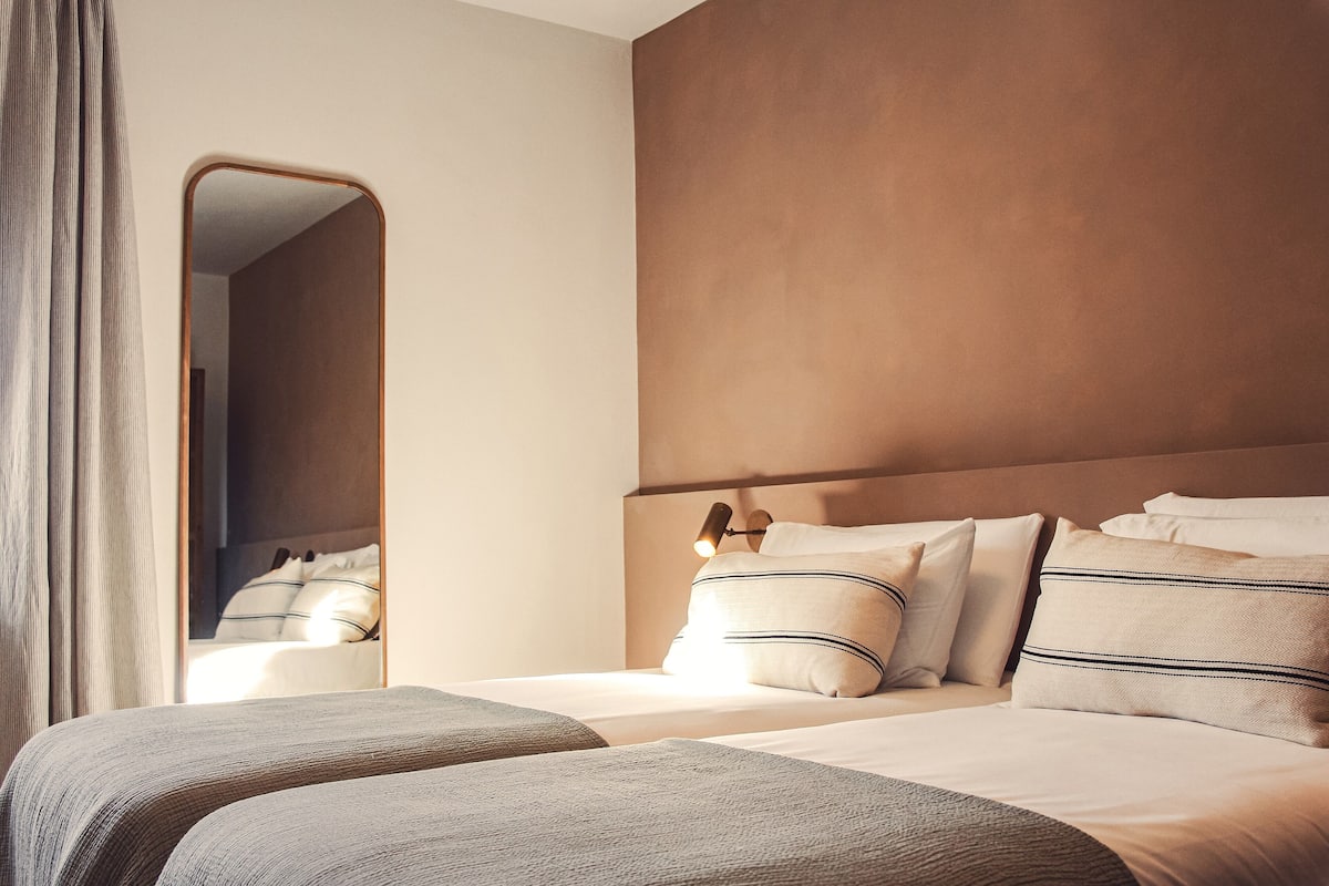Une chambre d’hôtel avec un lit, un miroir et une tête de lit.