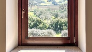 A room with a large window, a wooden door, and a view of a hilly landscape. - Agriturismo Scala – Eco Boutique B&B (Potenza Picena)