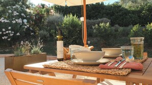 An outdoor dining table with a woven placemat, a bottle, bowls, glasses, and cutlery. - Agriturismo Scala – Eco Boutique B&B (Potenza Picena)
