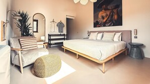 A bedroom with a bed, a chair, a round ottoman, a hanging light fixture, a painting, and a mirror. - Agriturismo Scala – Eco Boutique B&B (Potenza Picena)