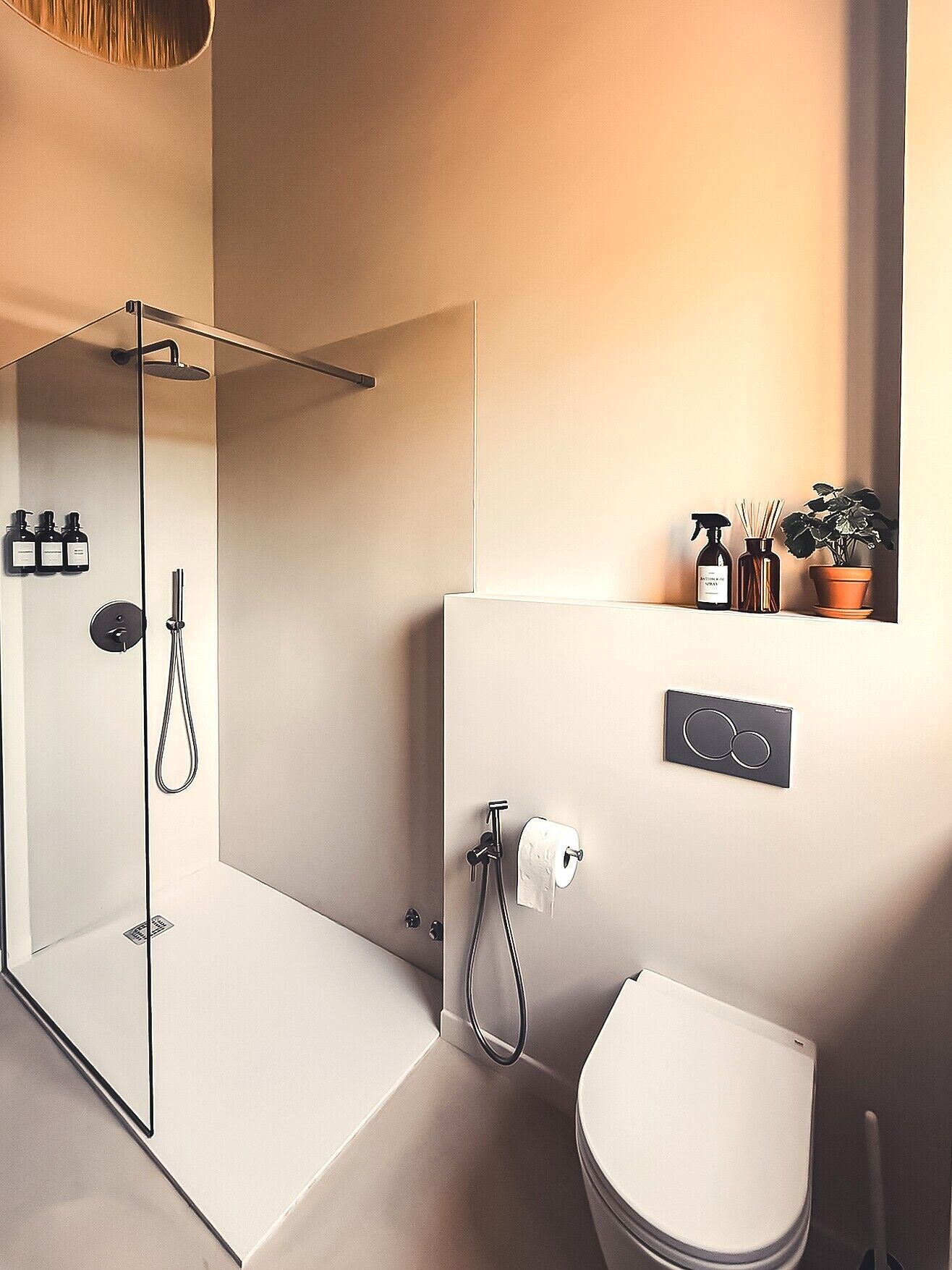 A modern bathroom with a glass shower enclosure, a toilet, and a sink area with toiletries.