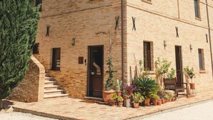 A two-story building with a brick facade, multiple windows, and a staircase leading to the entrance. - Agriturismo Scala – Eco Boutique B&B (Potenza Picena)