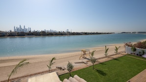 A beachfront property with a view of a city skyline, a sandy beach, and a playground.
