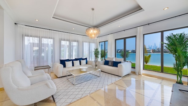 A modern living room with a sofa set, a coffee table, and a view of the city and water.