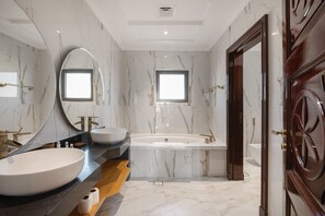 Une salle de bain moderne avec un grand lavabo ovale, une baignoire sur pieds et un meuble-lavabo avec un miroir.