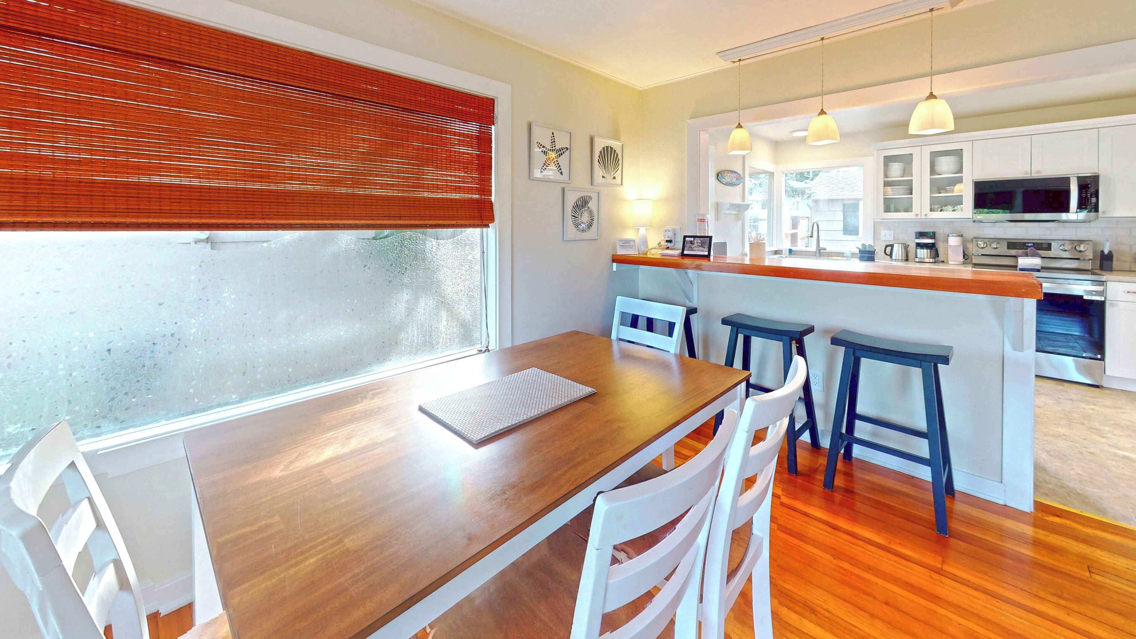 Una cocina moderna con armarios blancos, una mesa de comedor de madera y una barra.