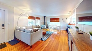 A modern living room with a sofa, coffee table, and dining area. - Georgie's Tide and True Cottage at Seaside Beach (Seaside)