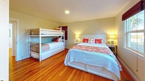 A bedroom with a bunk bed, a single bed, and a window with a view.