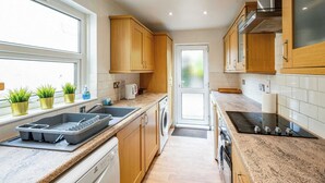 Eine Küche mit Holzausstattung, einem Backofen, einem Geschirrspüler und einem Fenster mit Blumentöpfen.