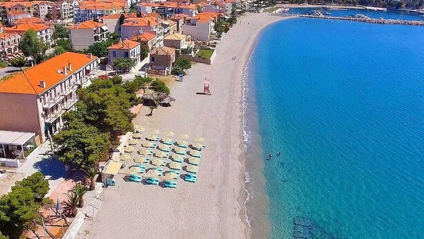 Une zone côtière avec une plage, des parasols et des bâtiments.
