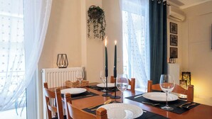 Un coin repas avec une table en bois mise pour quatre personnes, comprenant des assiettes, des couverts et des verres à vin.