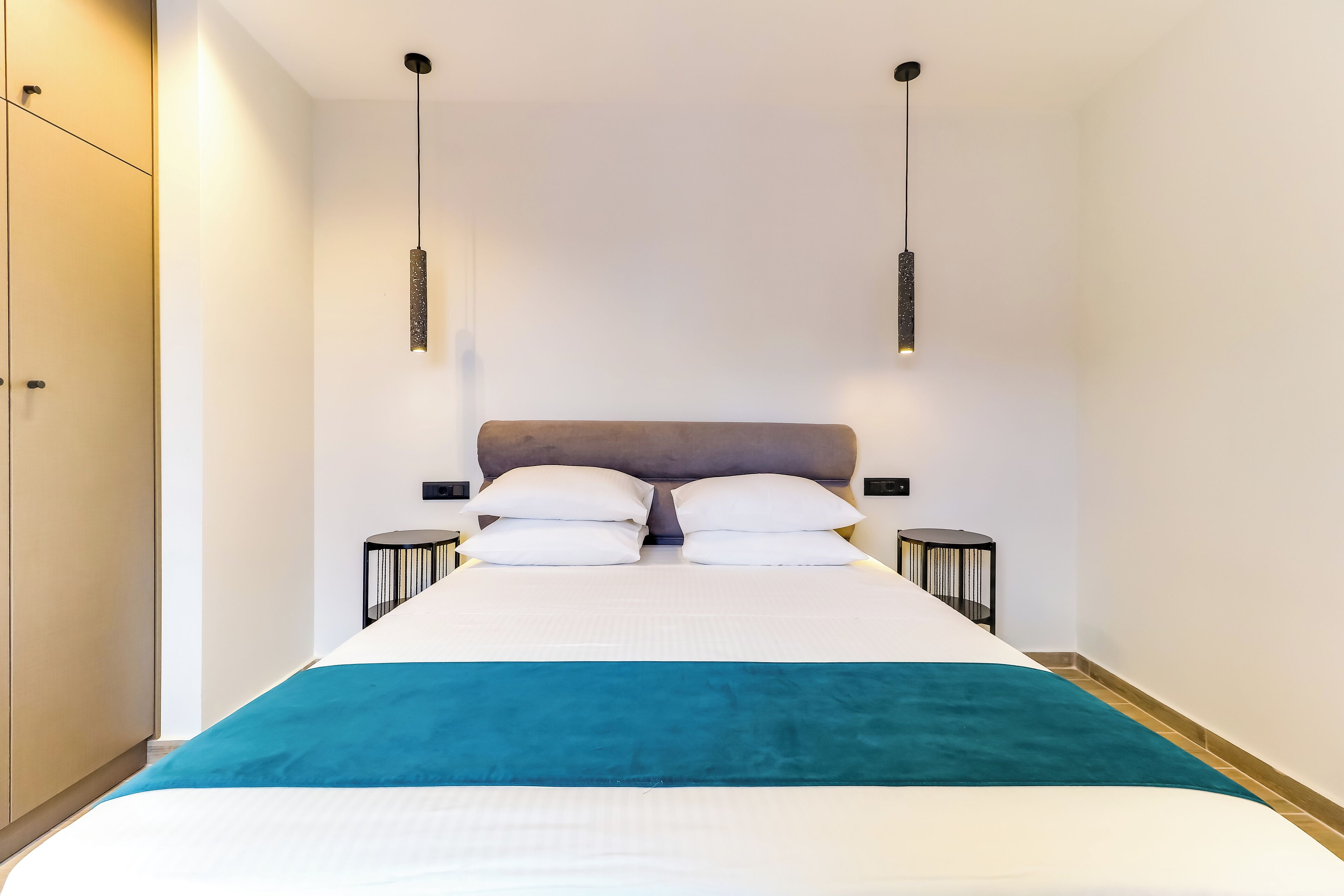 Una habitación de hotel moderna con una cama grande, dos mesitas de noche y un armario.