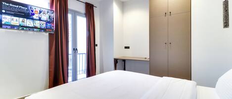 Une chambre d’hôtel équipée d’un lit, d’une armoire, d’un bureau et d’un téléviseur affichant la liste des chaînes.