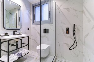 Un bagno moderno con cabina doccia in vetro, un WC bianco, una vaschetta con specchio e un porta asciugamani.