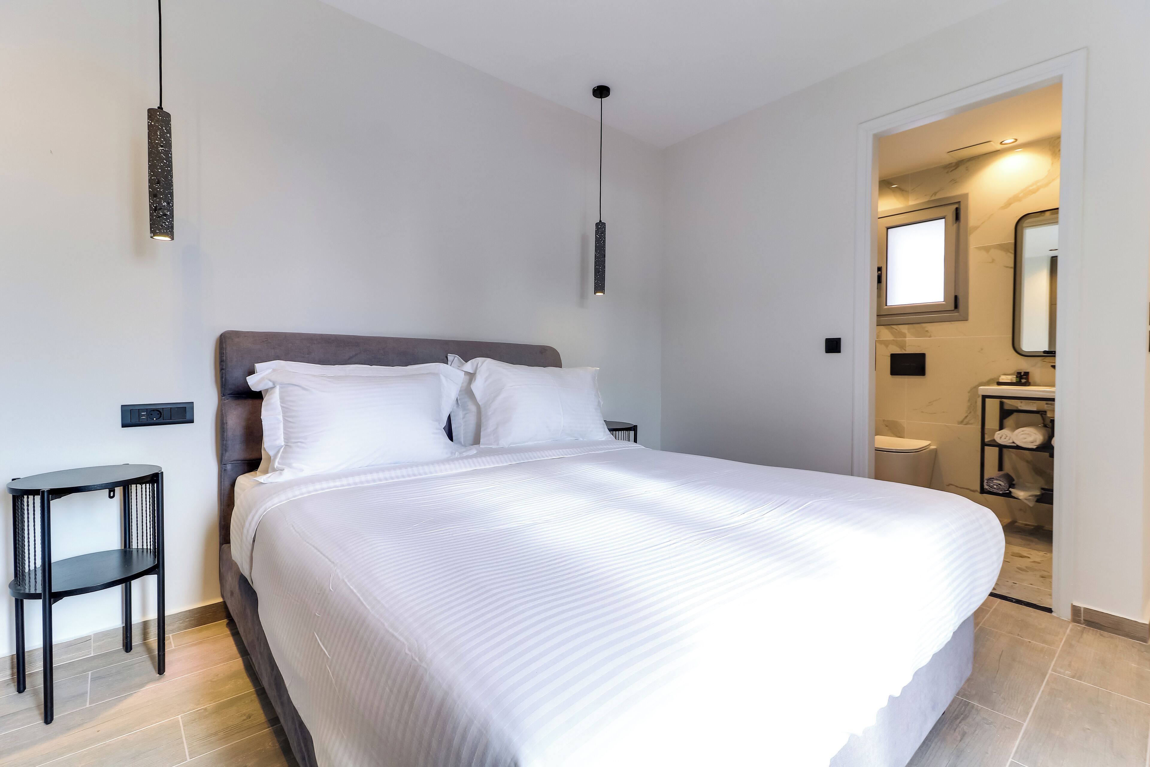 Een moderne slaapkamer met een groot bed, een nachtkastje en een hanglamp.