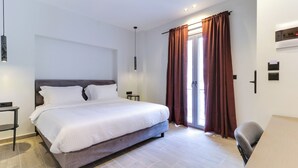 Une chambre à coucher moderne avec un grand lit, des tables de chevet, un bureau et une fenêtre avec des rideaux.