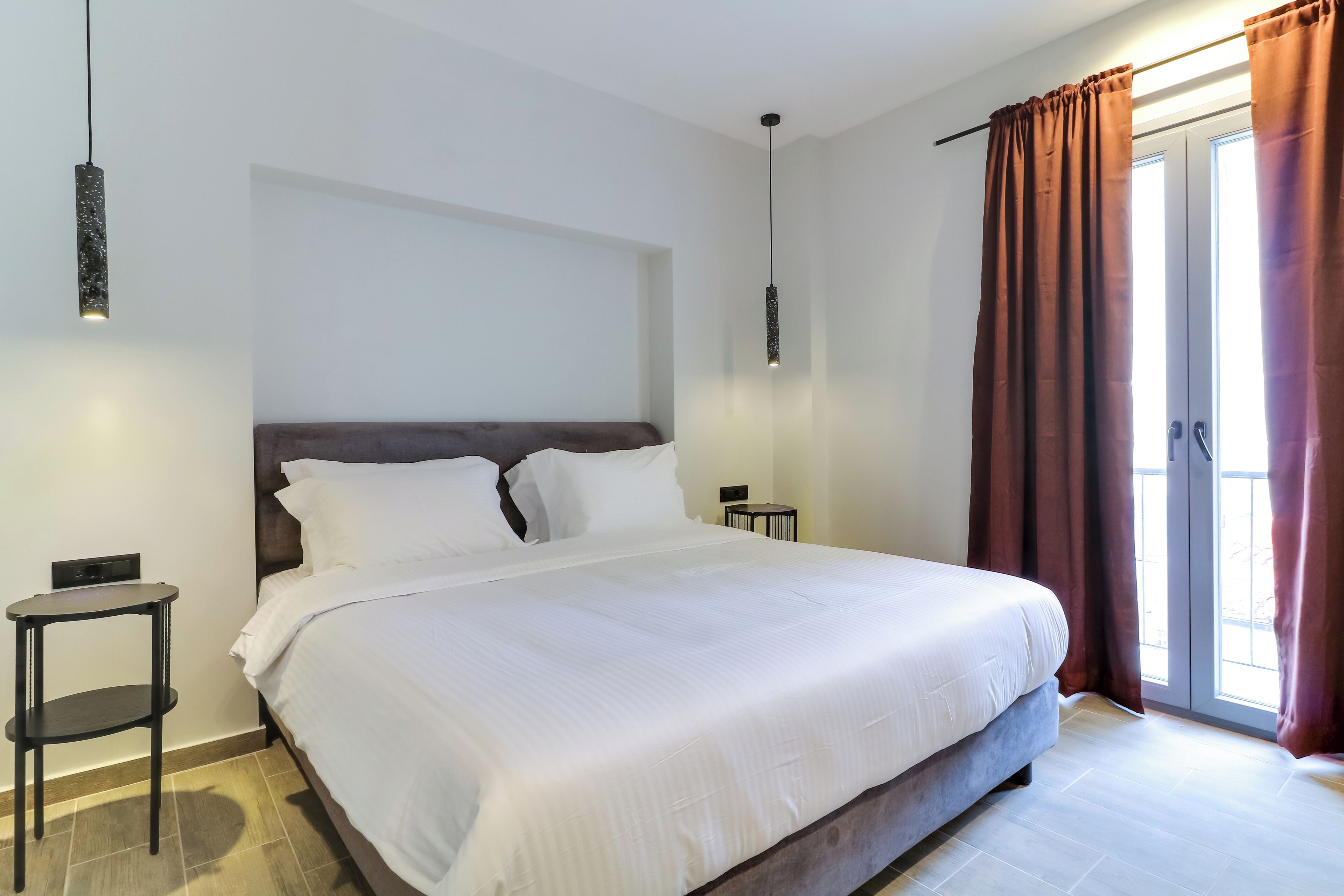 A neatly made bed with white linens, a dark headboard, and a small bedside table with a lamp.