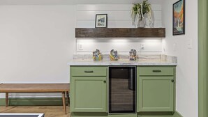 Una cocina con armarios verdes, horno empotrado y encimera de mármol.