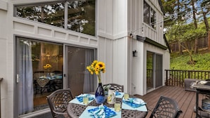 Un espace extérieur aménagé pour les repas, avec une table ronde, des chaises et un vase rempli de tournesols.