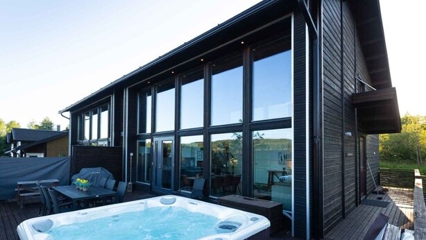 A modern building with large windows, a hot tub, and outdoor seating. - Villa Halla 2, HimosYkkösen alue (Jämsä)