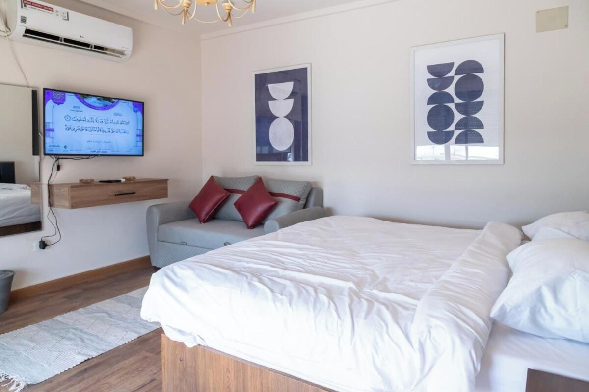 A modern bedroom with a large bed, a TV mounted on the wall, and artwork on the walls.