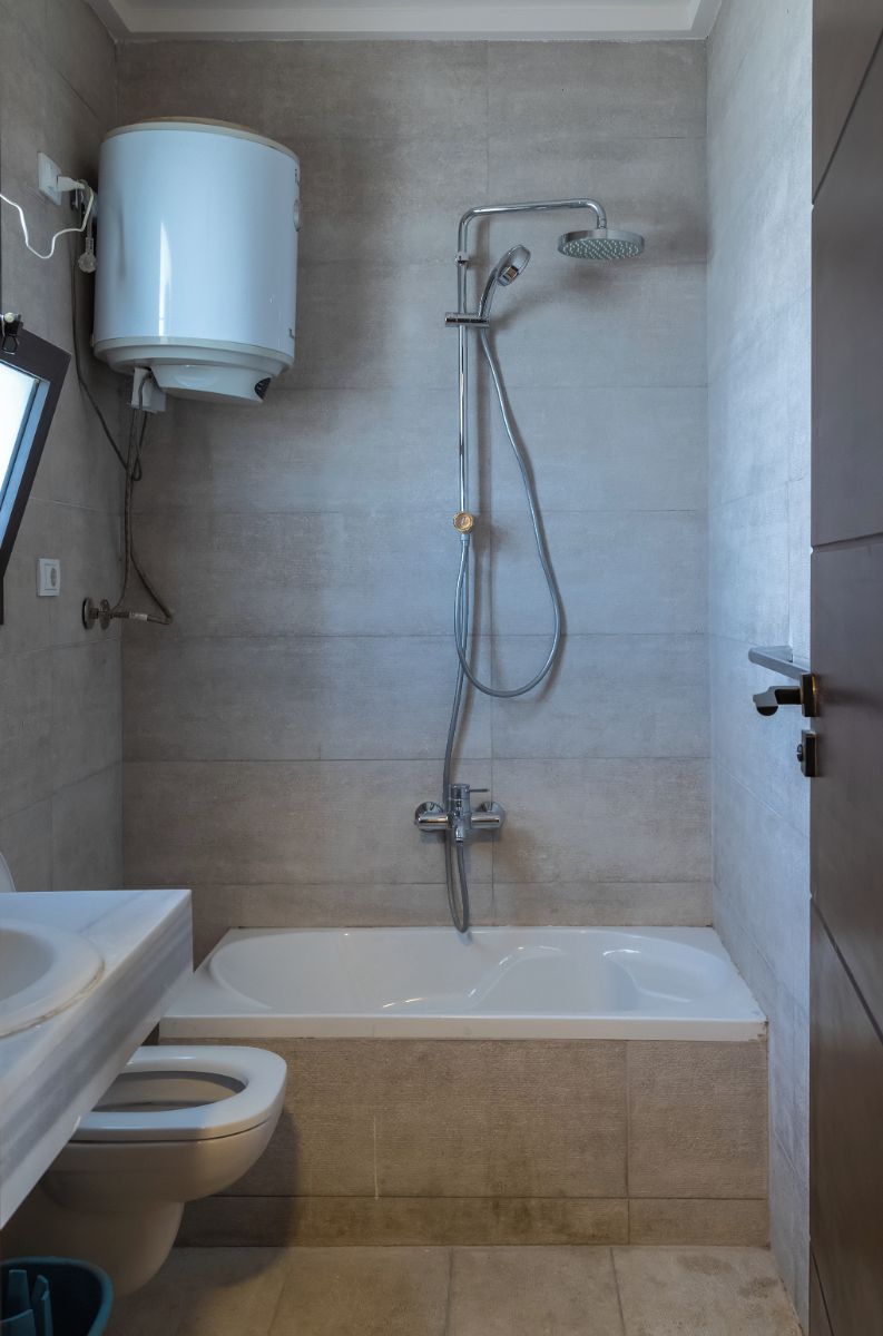 A bathroom with a toilet, bathtub, and a shower unit.