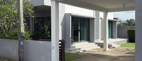 A modern two-story residential building with a covered driveway and a small front yard.