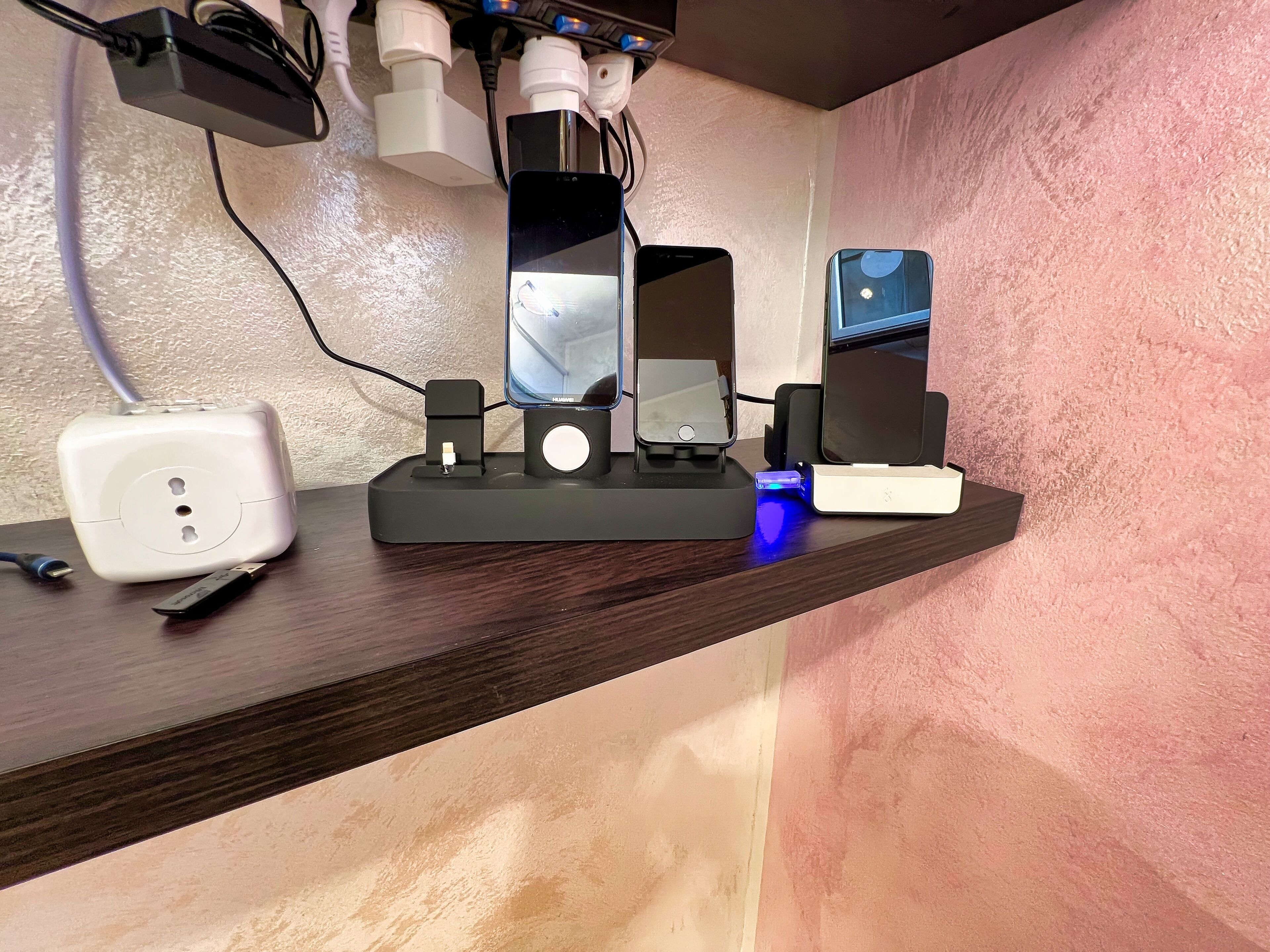 A desk with a power strip, a phone charging, a speaker, and a small blue light.