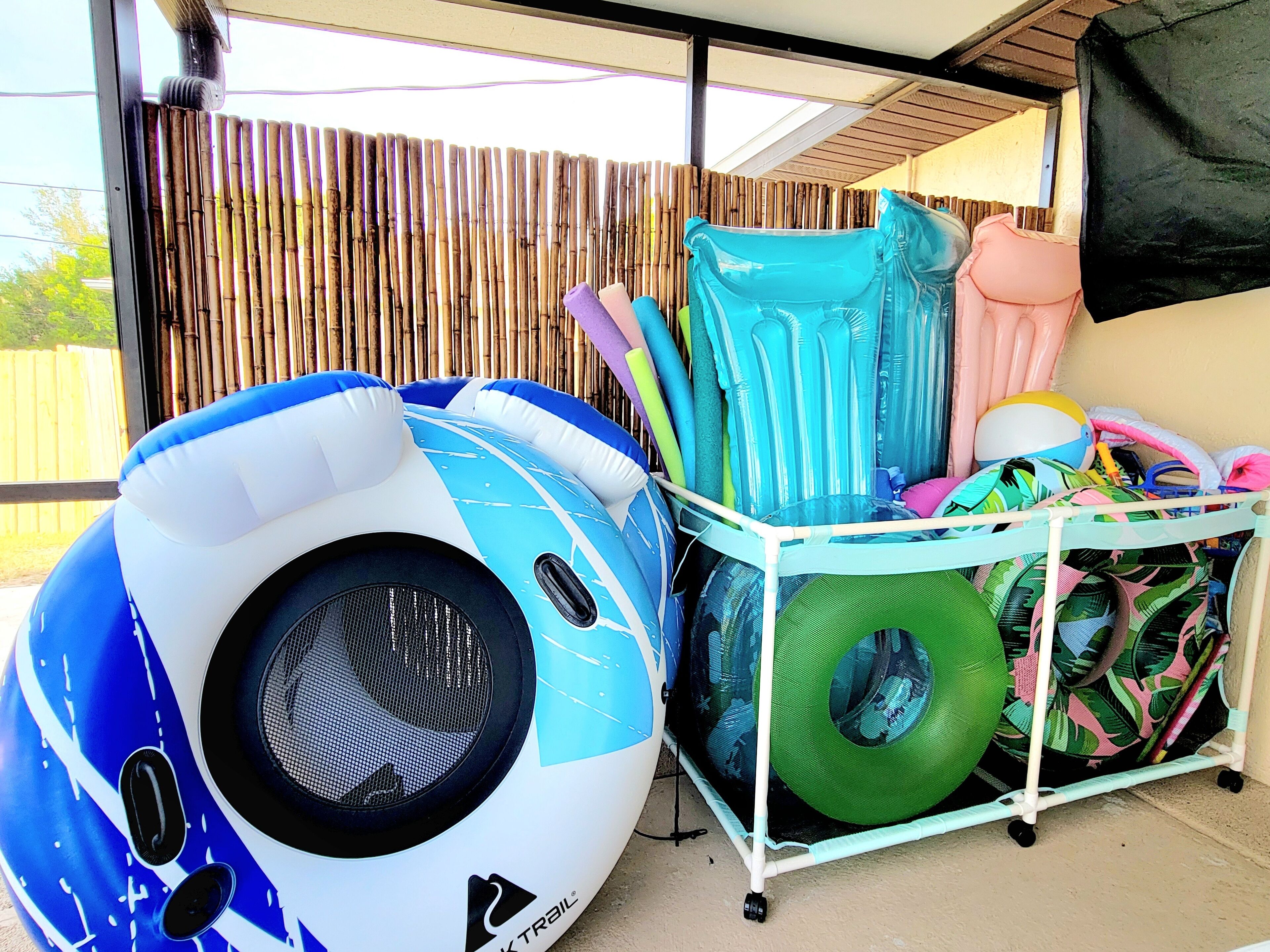 A poolside area with inflatable pool toys, a green inflatable ring, and a white metal rack.