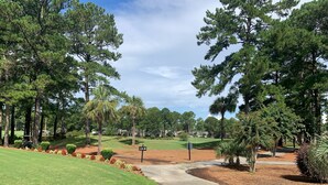 A golf course with a clear path leading to the tee area, surrounded by mature trees and well-maintained grass. - Relax, Beach, Golf, Shop, Repeat 2 Bedroom Resort (Calabash)