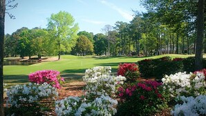 A golf course with a pond, surrounded by trees and flowering bushes. - Relax, Beach, Golf, Shop, Repeat 2 Bedroom Resort (Calabash)