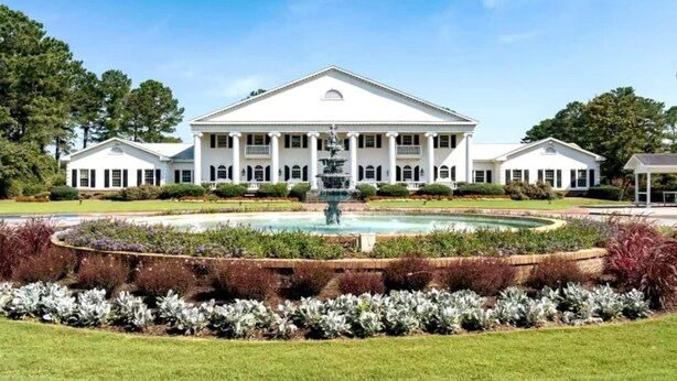 A large white building with a central fountain, surrounded by a well-maintained garden with various plants. - Relax, Beach, Golf, Shop, Repeat 2 Bedroom Resort (Calabash)