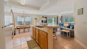 A modern kitchen with a central island, wooden cabinets, and a dining area with a table and chairs. - Relax, Beach, Golf, Shop, Repeat 2 Bedroom Resort (Calabash)