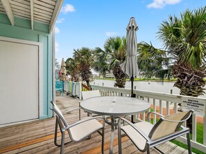 A deck with a round table and chairs, a covered umbrella, and a sign prohibiting BBQ pits on decks.