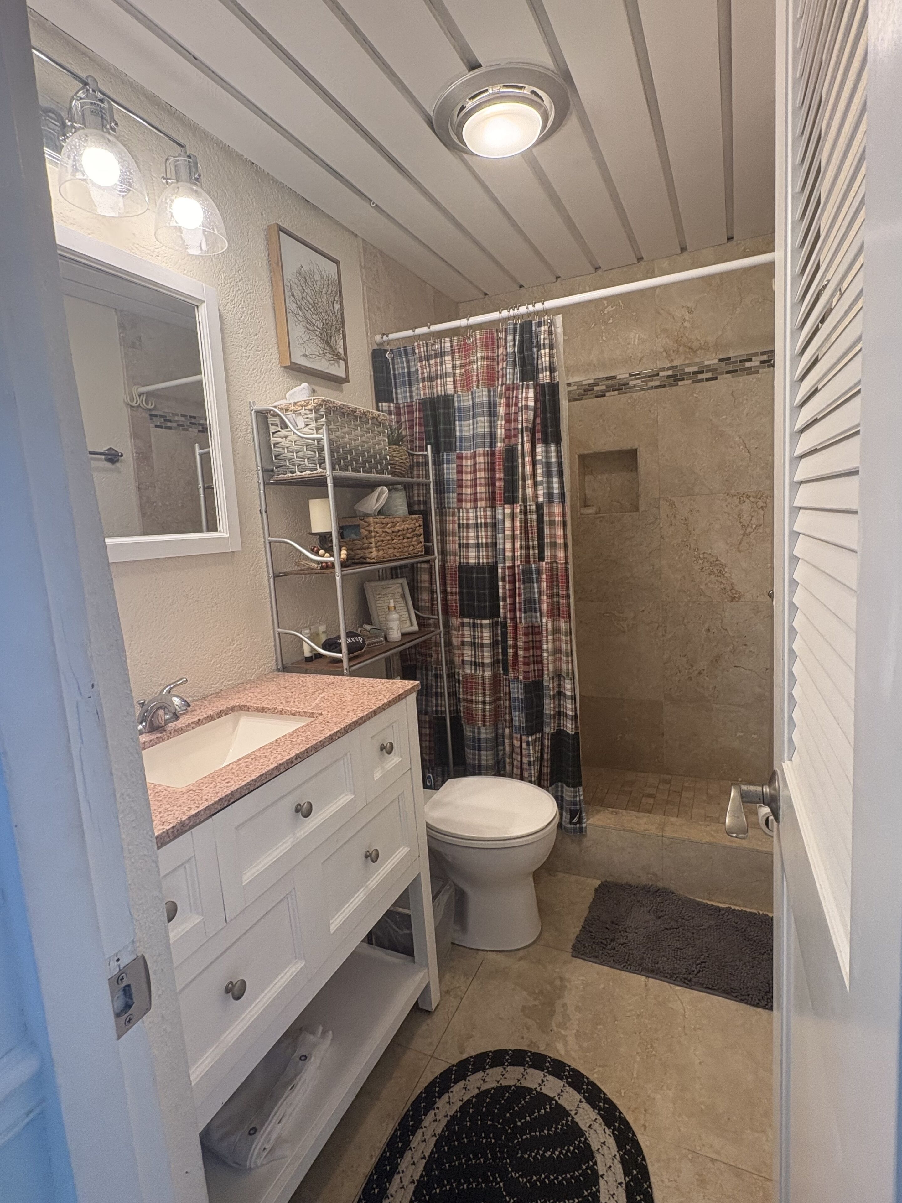 A bathroom with a toilet, sink, and mirror. There are towels and a shower curtain visible.