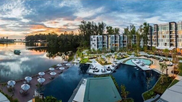 A resort with a large swimming pool, a dock, and modern buildings with balconies. - Cassia 1bdr by ISI (Choeng Thale)