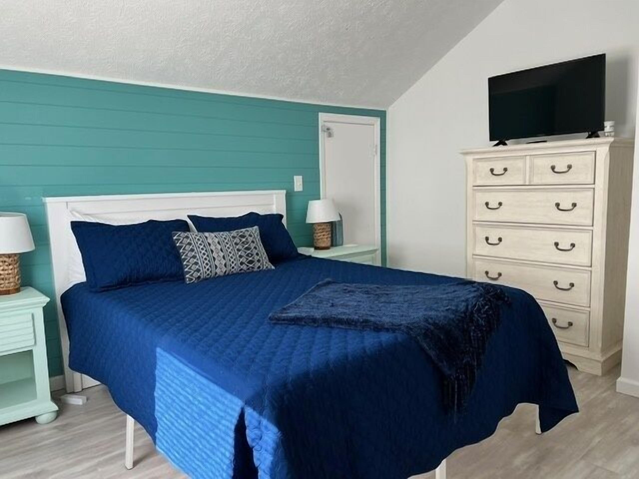 Une chambre à coucher avec un lit, des tables de chevet, une commode et un téléviseur.
