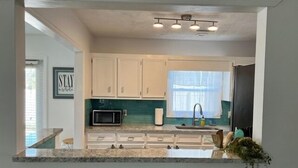 A kitchen with white cabinets, a microwave, a sink, and a window. - 604 Wedgewood 3 Bedroom Home (North Myrtle Beach)