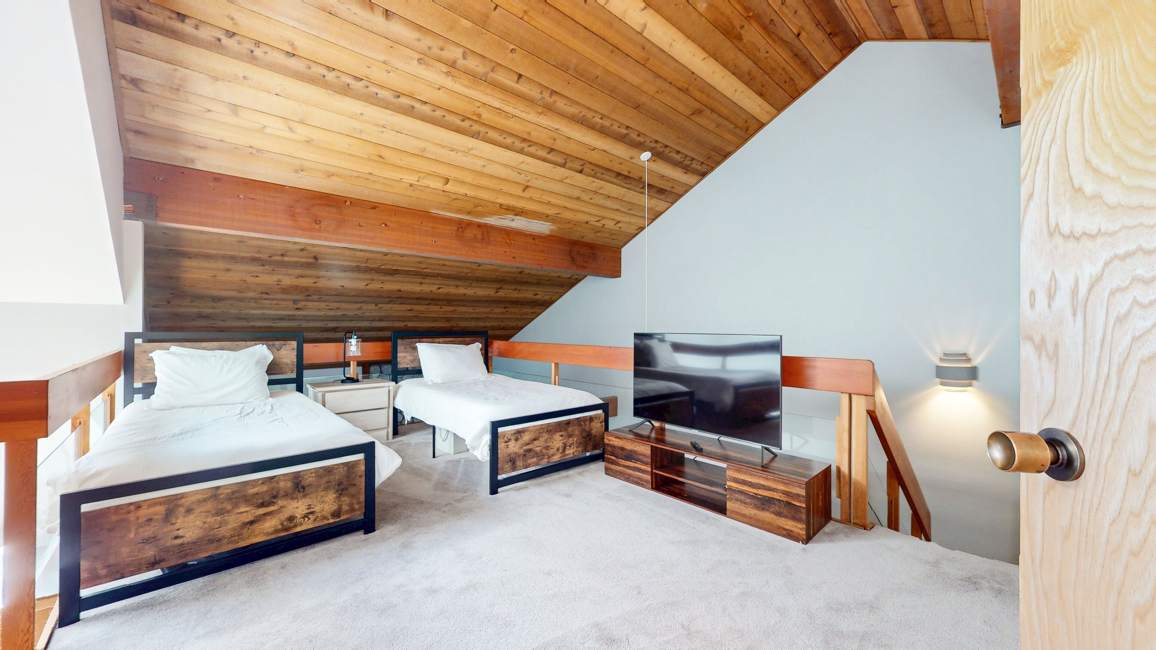 Een slaapkamer met twee bedden, een televisie en een houten plafond.