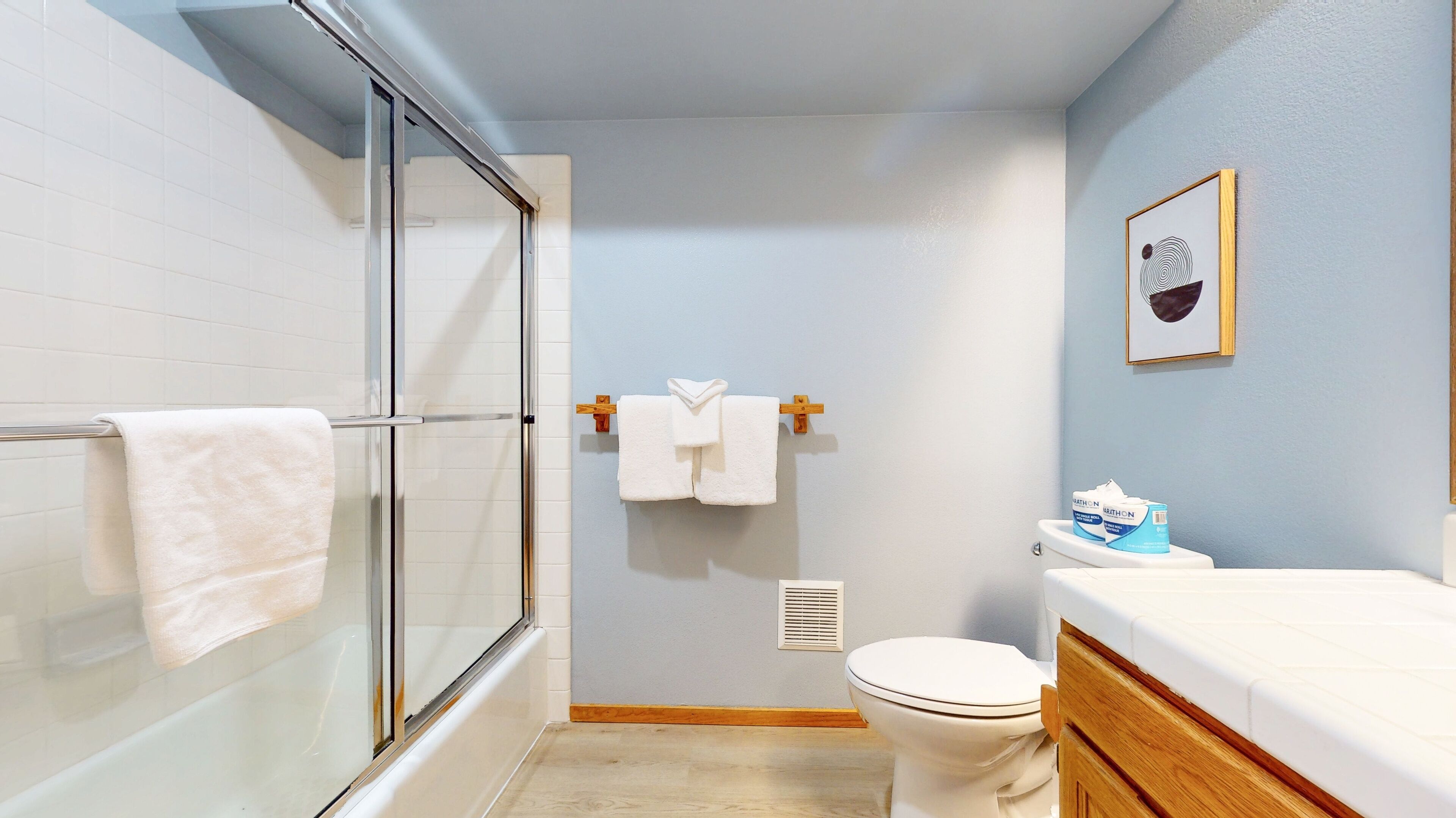 Une salle de bain dotée d’une douche à parois de verre, de toilettes et d’un lavabo avec un plan de travail en bois.