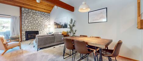 A dining area with a wooden table and chairs, a stone wall, and a fireplace.