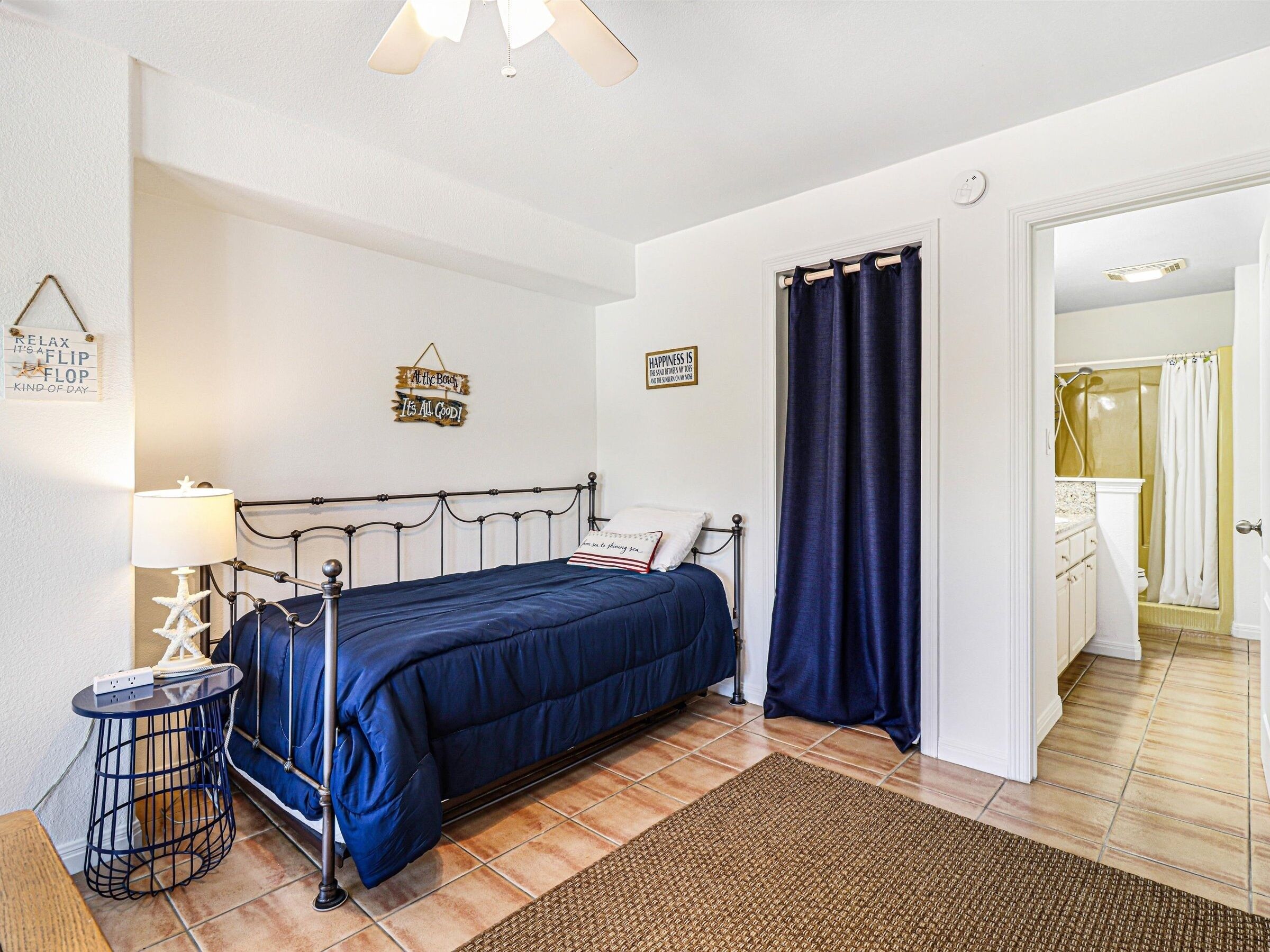 A bedroom with a bed, bedside table, lamp, and wall decorations.