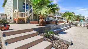 A building with a staircase leading to a balcony, palm trees, and a concrete water feature. - Bon Bini 4 Bedroom Home (Rockport)