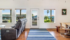 A room with a massage chair, a dining table, and large windows with views of buildings and greenery. - Bon Bini 4 Bedroom Home (Rockport)