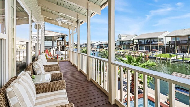 A covered outdoor area with wicker furniture and a view of a marina. - Bon Bini 4 Bedroom Home (Rockport)