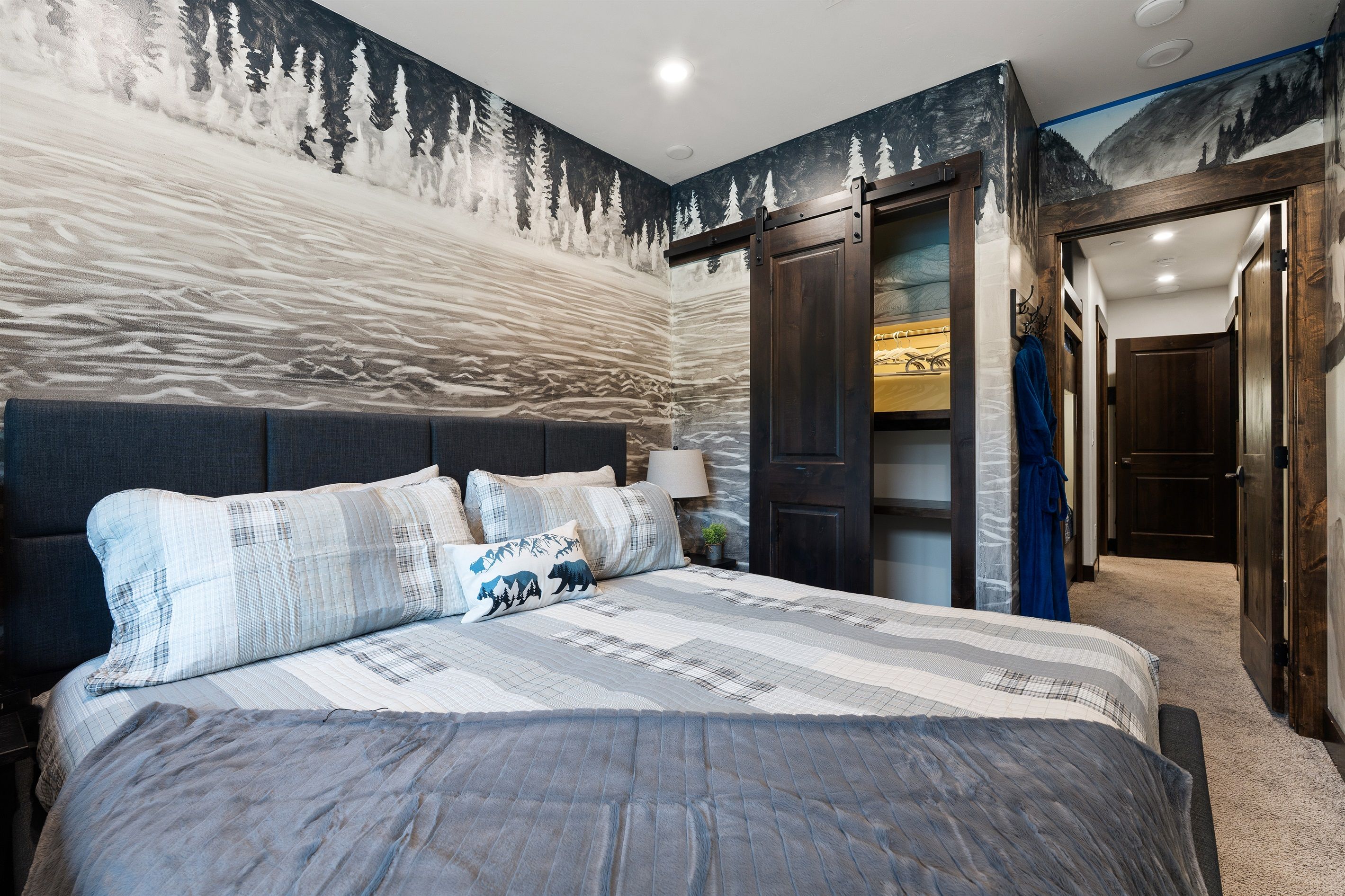 Une chambre à coucher avec un grand lit, une armoire et une porte donnant sur une autre pièce.