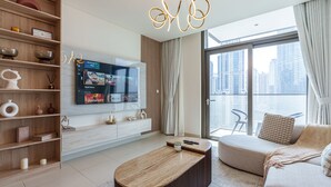 Een moderne woonkamer met een flatscreen televisie waarop een streamingdienst draait, een houten boekenkast, een ronde salontafel, een bank en een stadsgezicht door grote ramen.