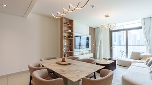 Een moderne woonkamer met een eethoek, een ingebouwde televisie en een groot raam met uitzicht op de stad.