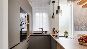 Een moderne keuken met een inbouwoven, een spoelbak en een houten aanrecht.