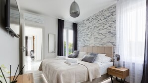 Een moderne slaapkamer met een groot bed, nachtkastjes, een spiegel en uitzicht op de omgeving.